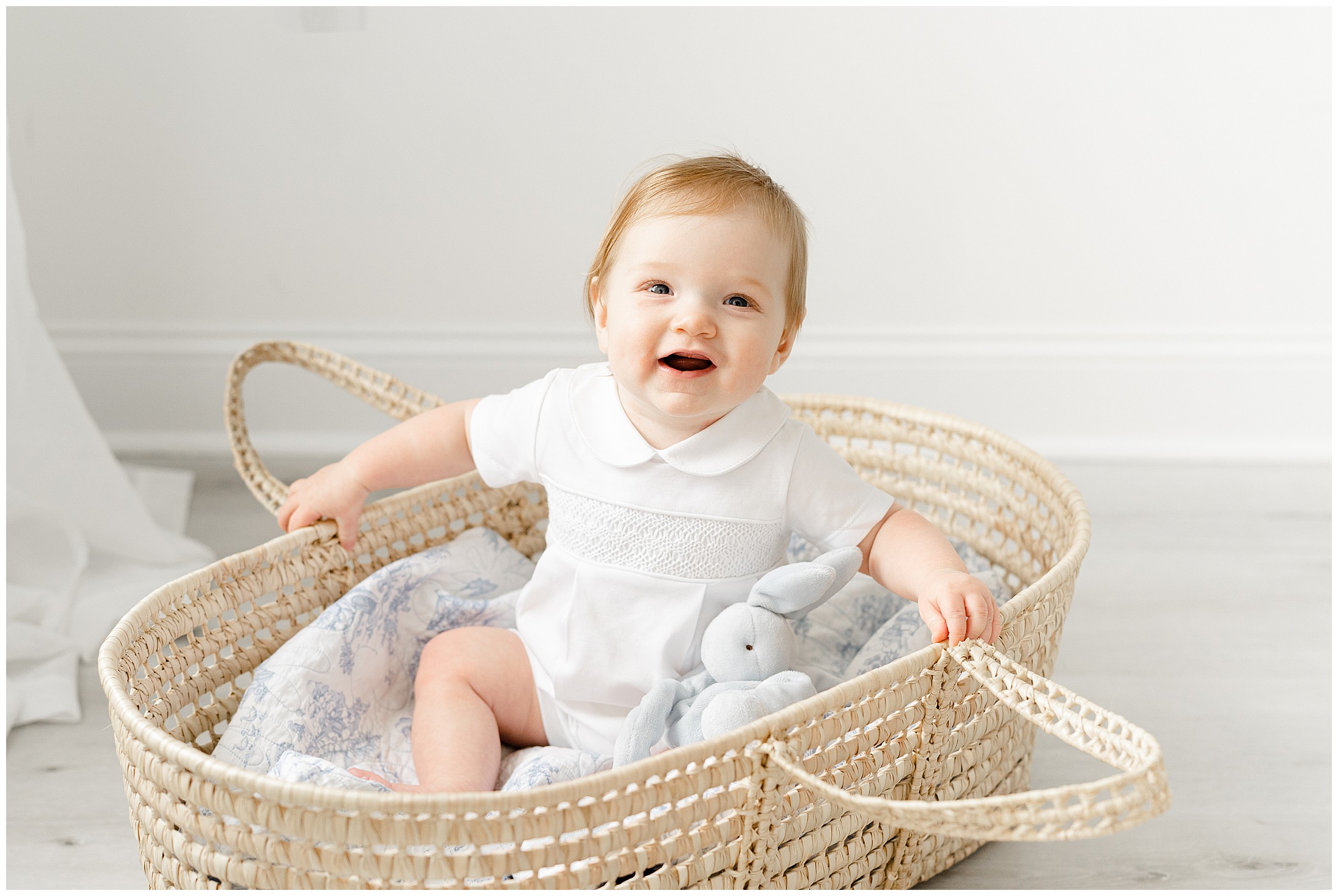6 month old baby sitting in a Moses basket smiling for a photo by Atlanta Georgia photographer Lindsey Powell.
