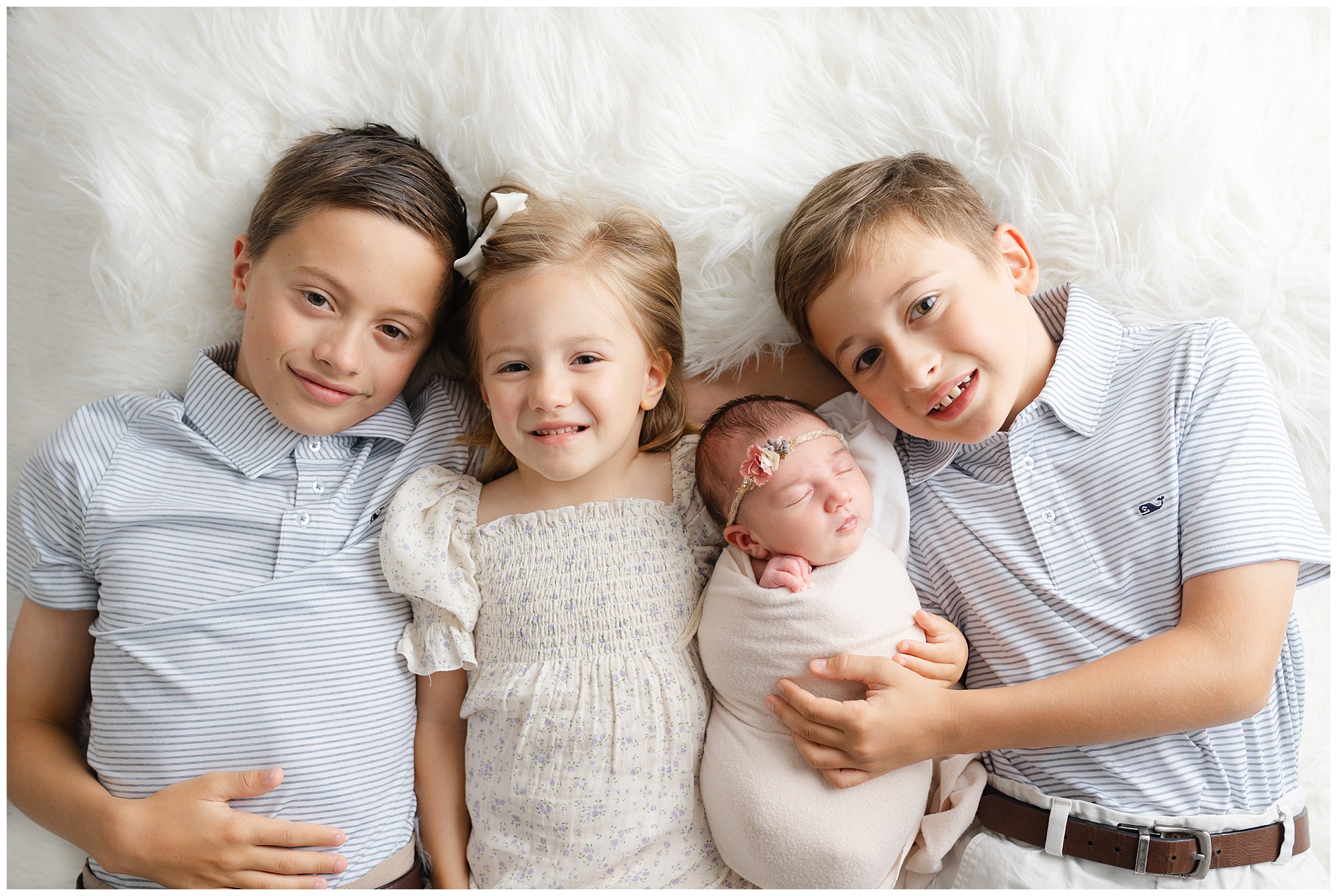 Marietta newborn portraits of a baby with her three older siblings lying down and looking up at camera.