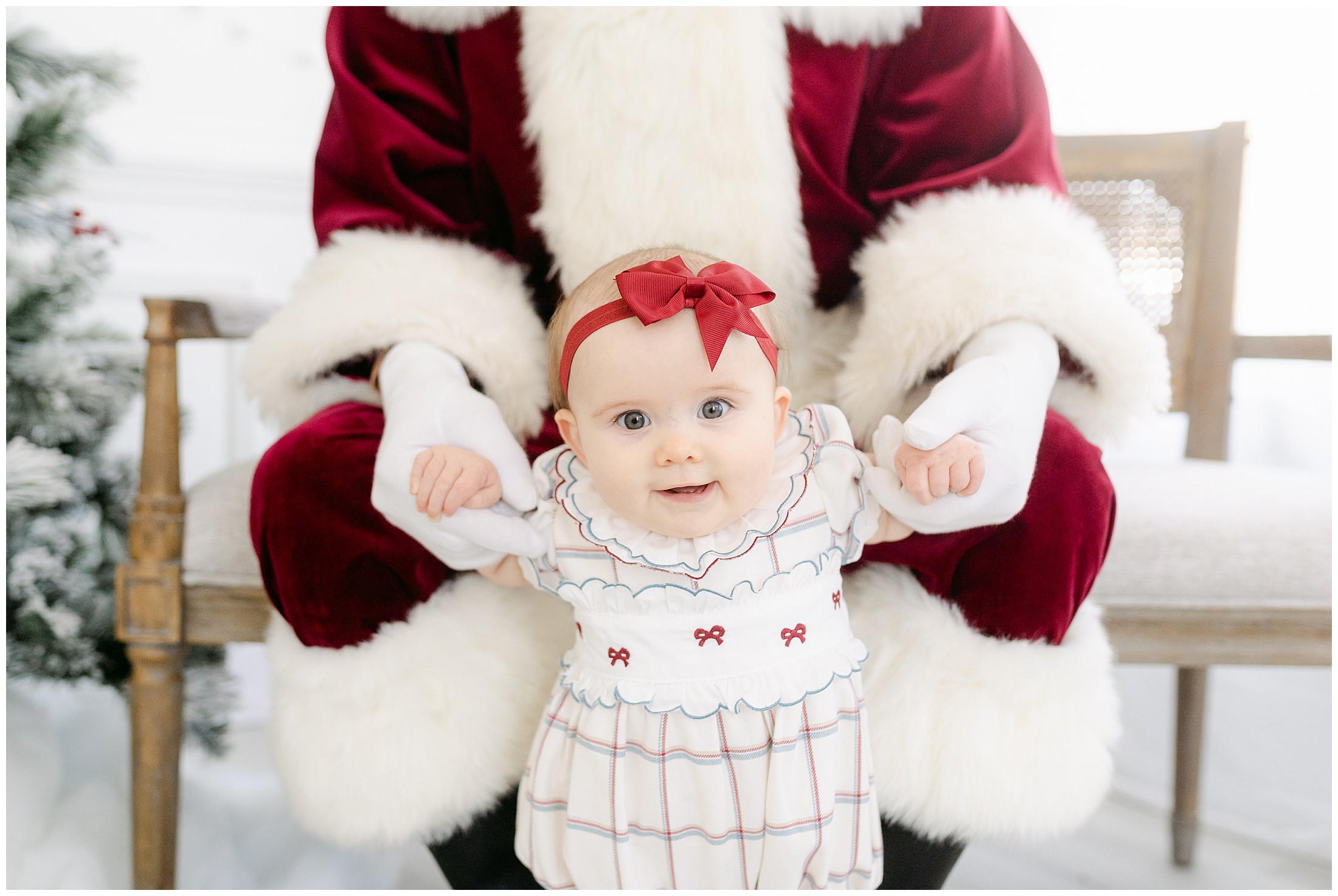 Baby standing while Santa holds her hands to help her stand.