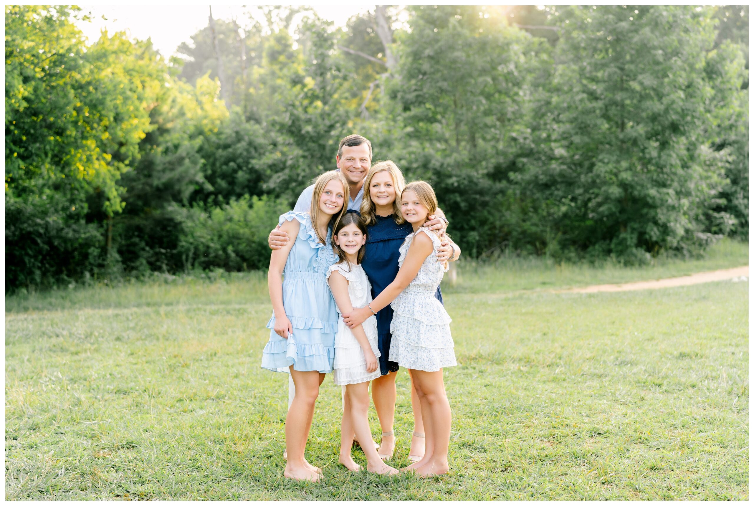 Portrait of a family smiling and posing in a field for a photographer in Atlanta.