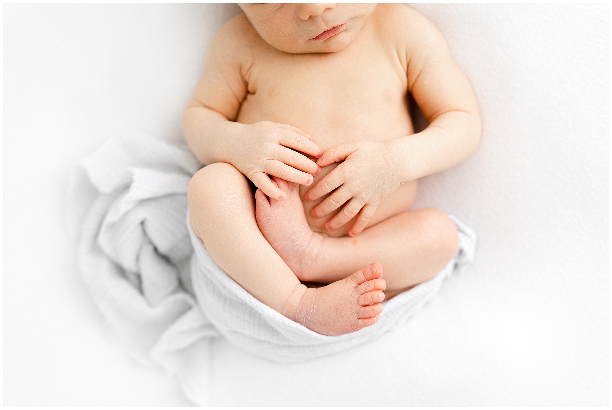 Portrait of a newborn baby's legs and hands folded.