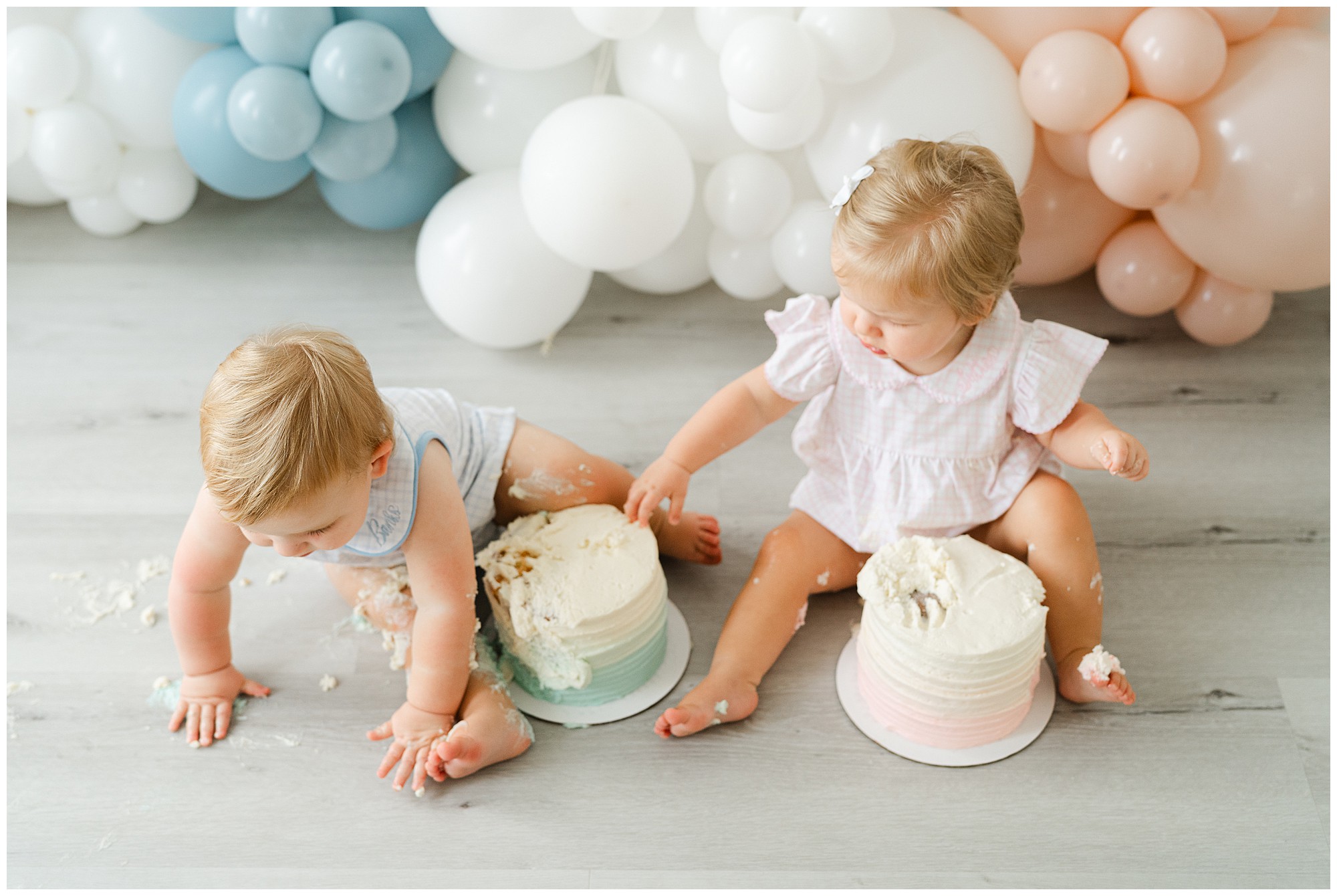 A twin boy and girl digging into cakes for an Atlanta cake smash for twins photo session.