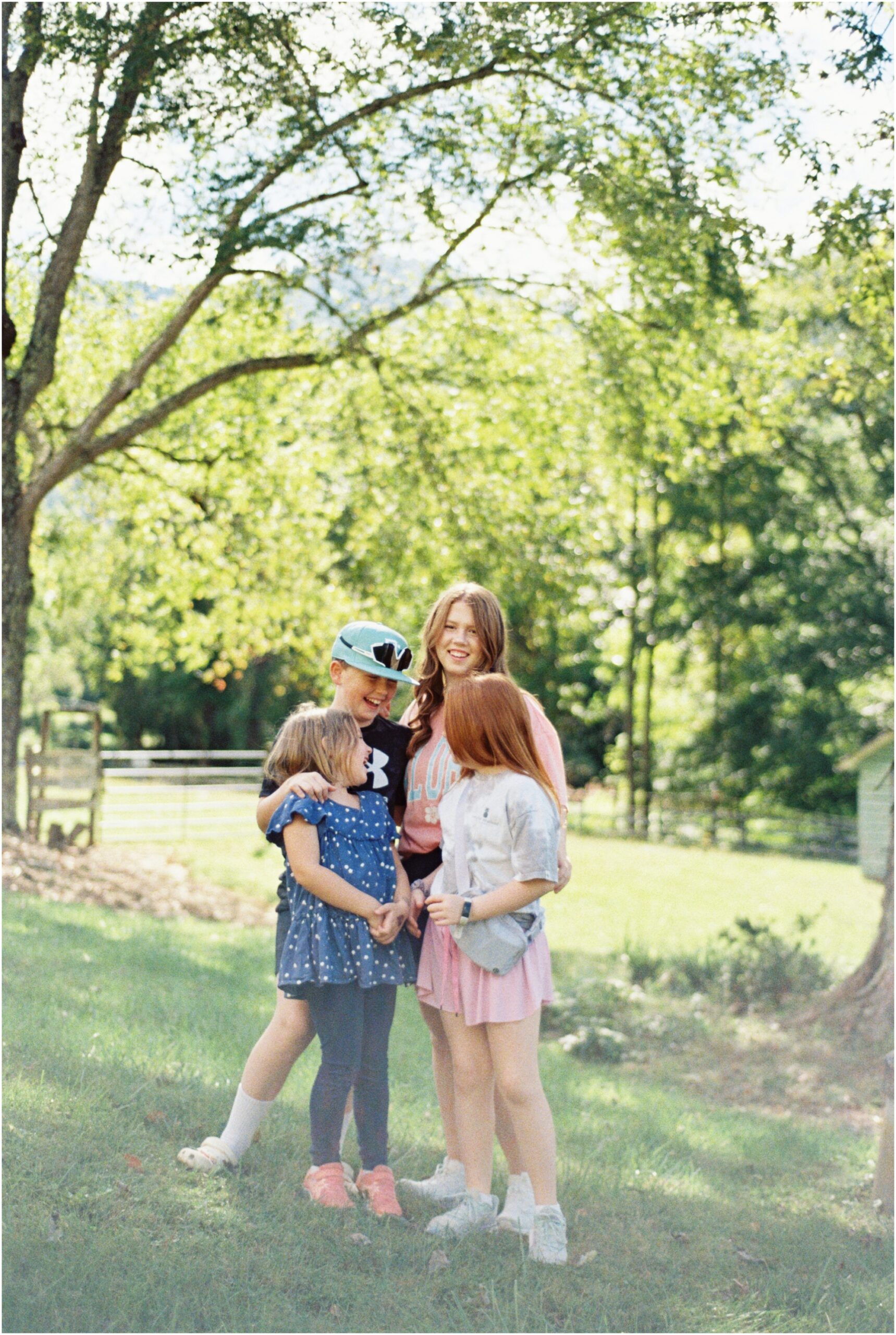 Four siblings stand with arms around one another smiling at each other at a Marietta park.